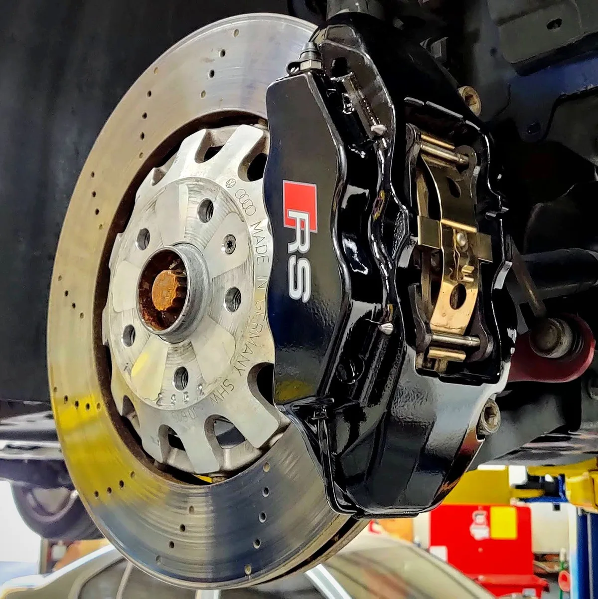An Audi RS brake, drilled rotor and caliper stamped Made in Germany, up on the lift