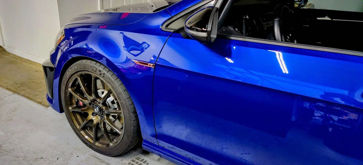 Bronze wheel and red brake caliper on a blue Volkswagen Golf R